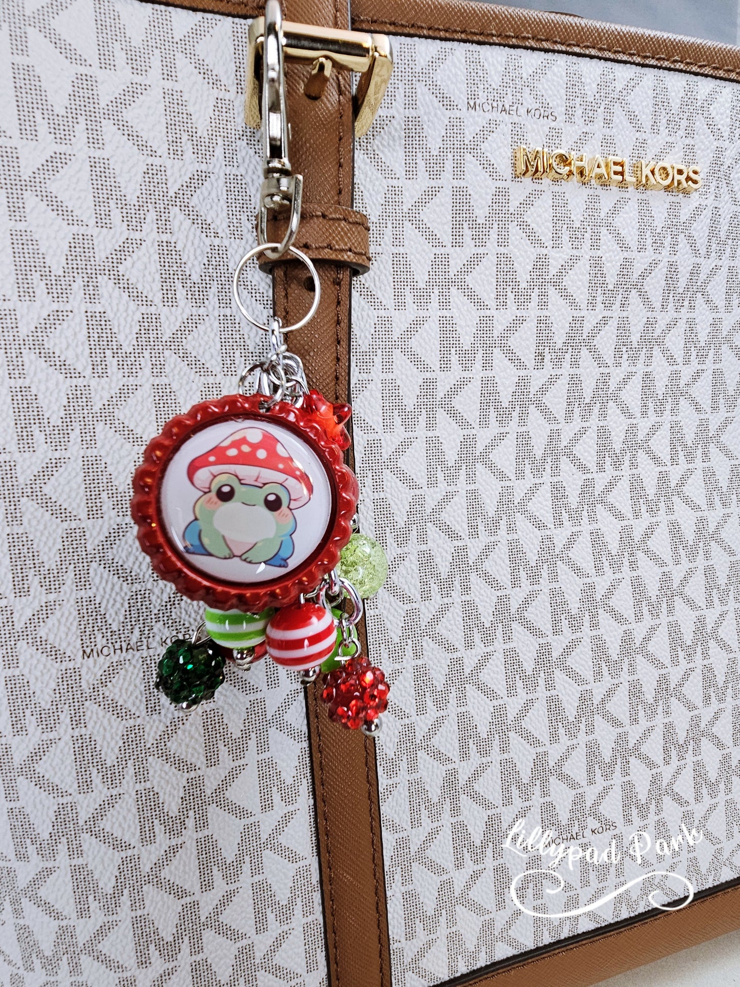 A colorful beaded bag charm featuring a whimsical frog wearing a mushroom cap, with red and green beads and a bottle cap charm.